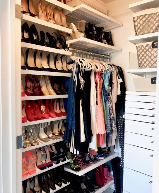 White closet organized with shoes and clothes.